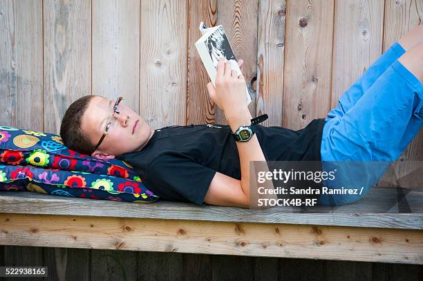 boy lying on bench reading book - 243 2013 stock pictures, royalty-free photos & images