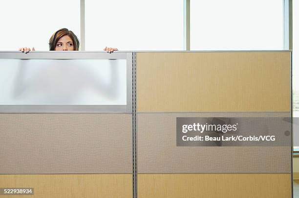 businesswoman peeking over cubicle wall - peeking cubicle stock pictures, royalty-free photos & images