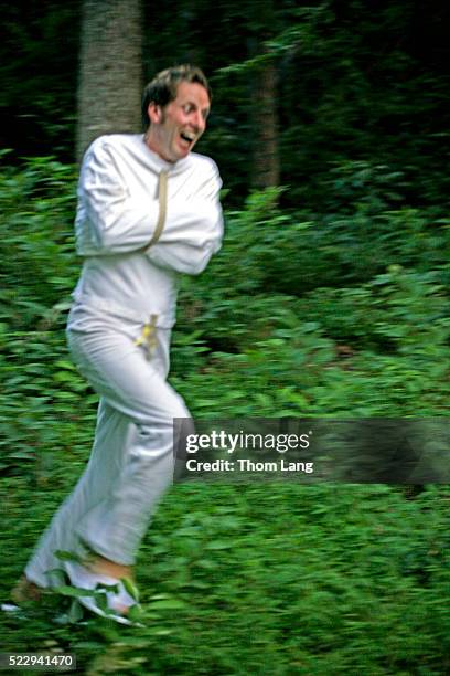 escaped mental patient running through woods - straitjacket foto e immagini stock