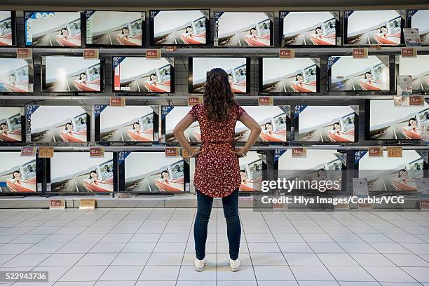 back view of woman standing in electronics store - tv store stock pictures, royalty-free photos & images