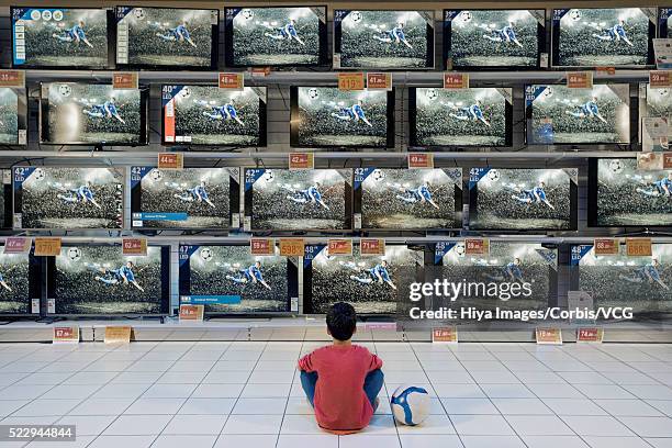 back view of boy watching soccer in electronics store - sport shop stock-fotos und bilder