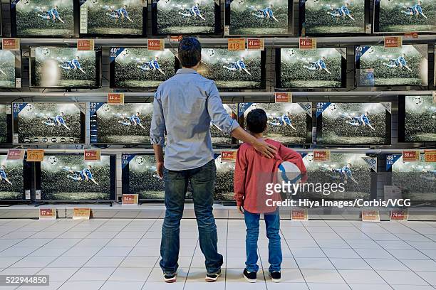 father and son watching soccer in electronics store - tv store stock pictures, royalty-free photos & images