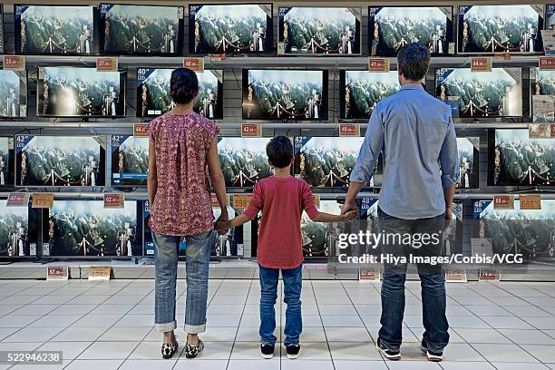 back view of family standing in electronics store against flat panel televisions display - family from behind stock pictures, royalty-free photos & images