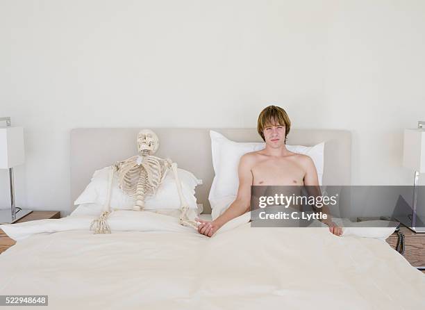 man lying in bed next to skeleton - aids activism stock pictures, royalty-free photos & images