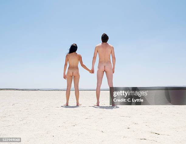 naked couple standing in desert - rendre les armes photos et images de collection