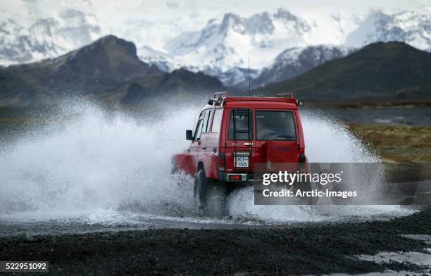 off-road vehicle crossing river in iceland - suv stock-fotos und bilder