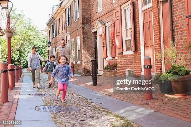 family and daughter (6-7) running along town street, philadelphia, pennsylvania, usa - philadelphia townhouse homes stock pictures, royalty-free photos & images