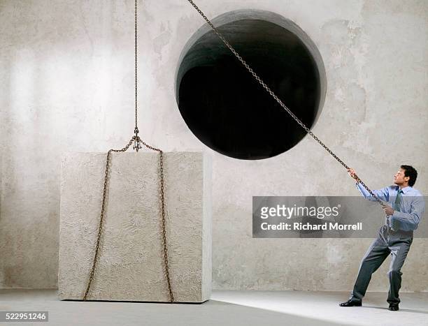 businessman trying to lift cube into round hole - pulley stock pictures, royalty-free photos & images