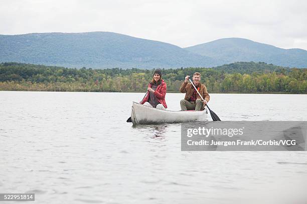 couple puddling in canoe on lake - puddling stockfoto's en -beelden