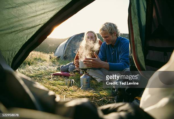 couple boiling water outside tent - camping couple stock pictures, royalty-free photos & images