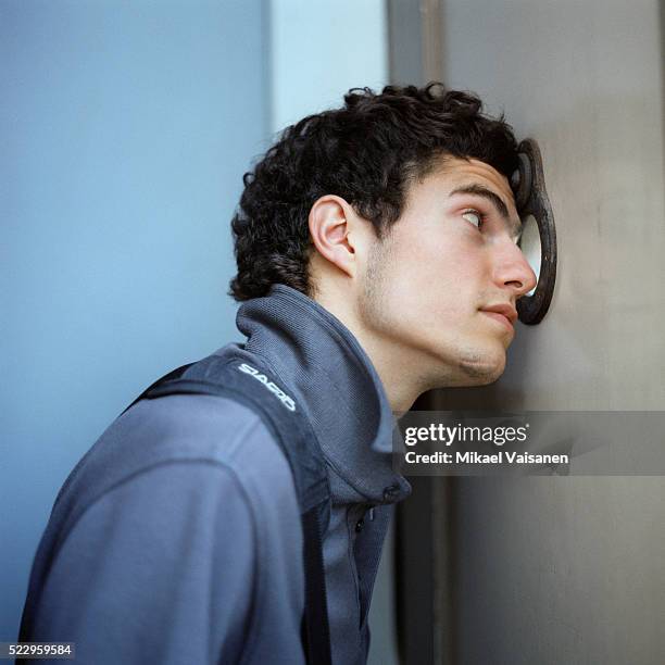 young man looking through peephole - peephole stock pictures, royalty-free photos & images