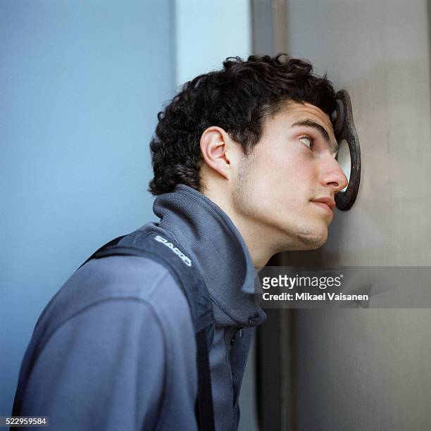 young man looking through peephole - kikhål bildbanksfoton och bilder