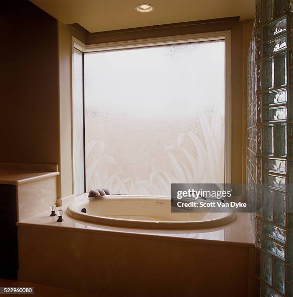 dim bathroom with etched-glass window behind tub - bath mat stockfoto's en -beelden