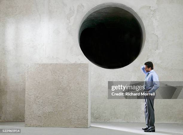 businessman trying to put square peg in round hole - square peg square hole stock pictures, royalty-free photos & images