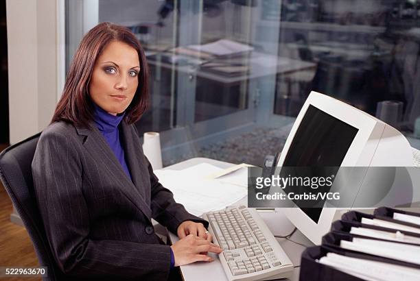brunette businesswoman at her desk - brunette sitting at desk stock-fotos und bilder