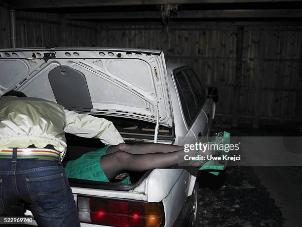 man putting body of woman in trunk - trunk fotografías e imágenes de stock