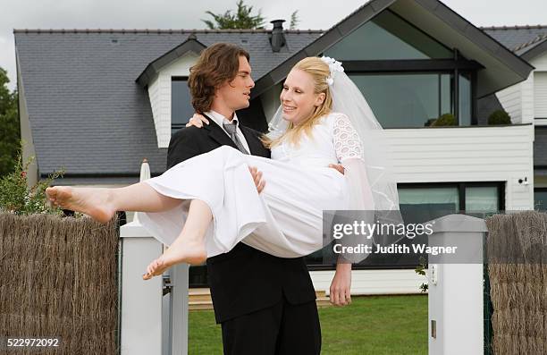 groom carrying bride through front gate - carrying bride stock pictures, royalty-free photos & images