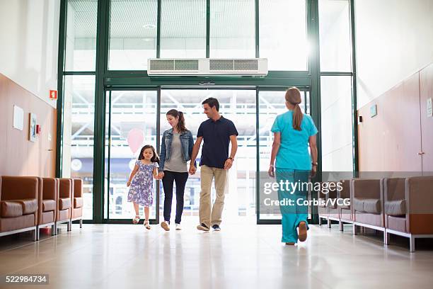 girl (6-7) entering hospital with parents - entering hospital stock pictures, royalty-free photos & images