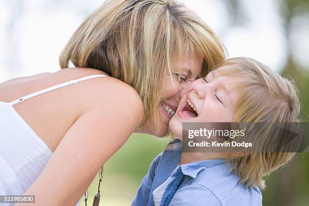 mother kissing son - wange an wange stock-fotos und bilder