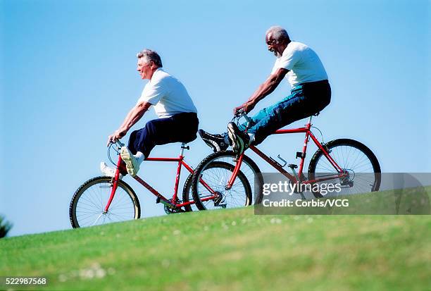 seniors riding bikes downhill - fahrrad fahren alte leute beine stock-fotos und bilder