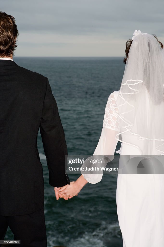 Bride and Groom Holding Hands by the Sea