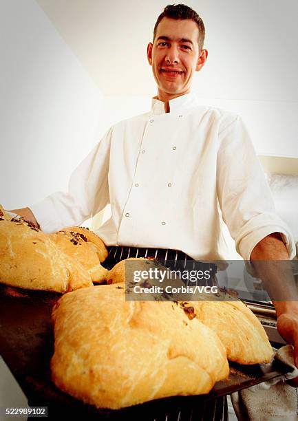 baker with fresh loaves of bread - baker smelling bread stockfoto's en -beelden