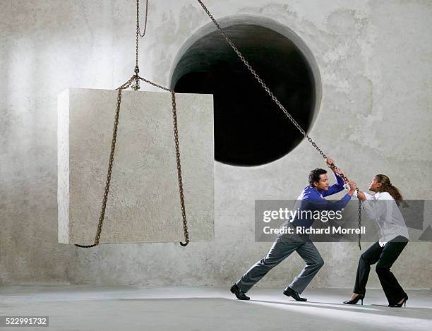 businesspeople trying to lift cube into round hole with pulley - round two bildbanksfoton och bilder