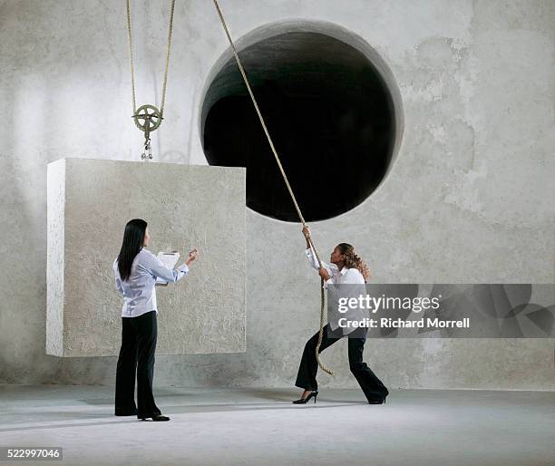 businesswomen trying to get block into round hole - pulley stock pictures, royalty-free photos & images