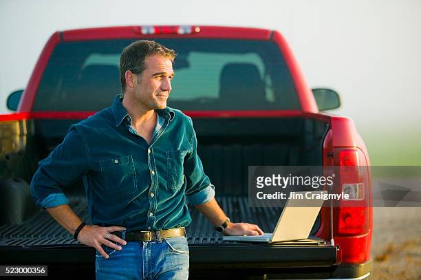 farmer using laptop from tailgate of truck - jim farmer stock pictures, royalty-free photos & images