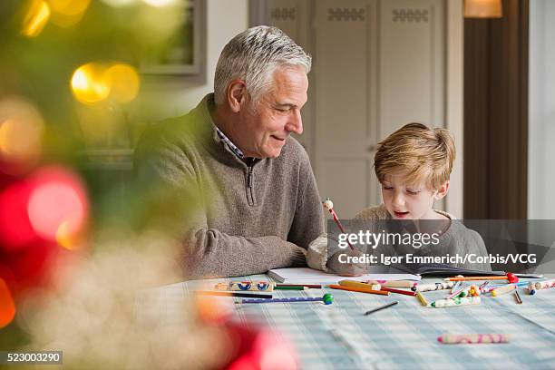 senior man looking on as boy colors - christmas colouring stock pictures, royalty-free photos & images