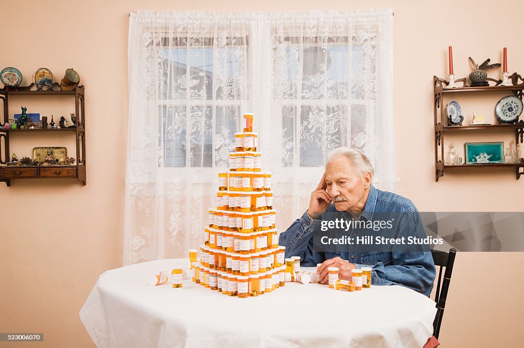 Senior Man Staring at Stack of Prescription Bottles