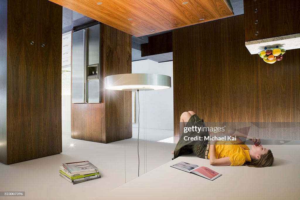 Young woman eating apple and lying on ceiling