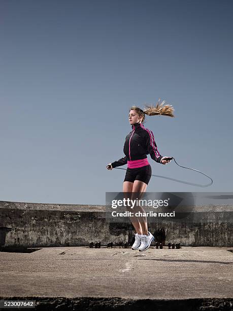young woman jumping rope outdoors - seilspringen stock-fotos und bilder