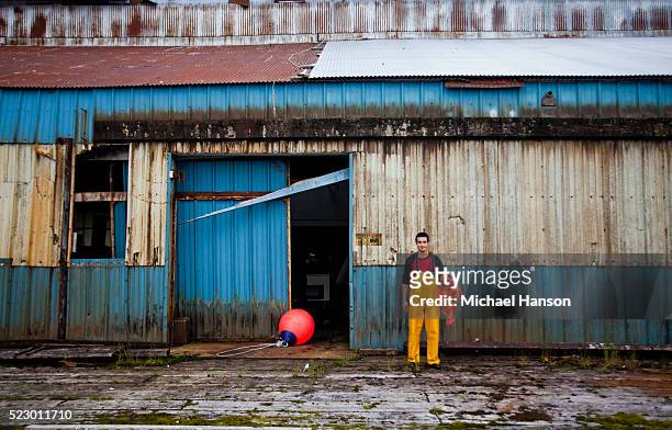 young fisherman holding large red fish by abandoned warehouse - waders stock-fotos und bilder