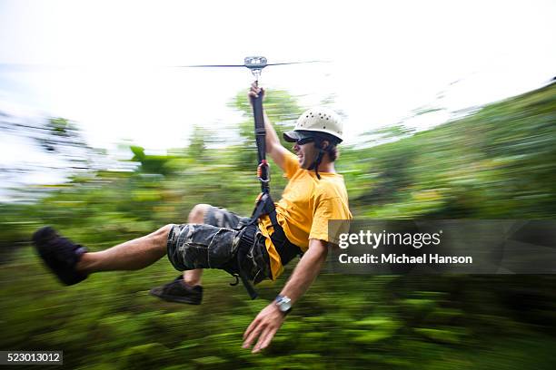 young man riding a zip line - zip line stock-fotos und bilder