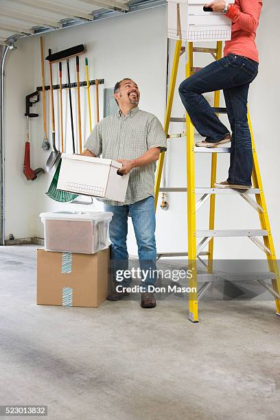 couple putting boxes into attic above garage - attic storage bildbanksfoton och bilder