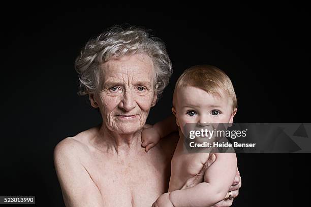 nude senior woman holding baby boy - baby studio shot stock pictures, royalty-free photos & images