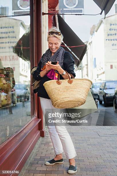 woman texting while window shopping, carcassonne, france - carcassonne imagens e fotografias de stock