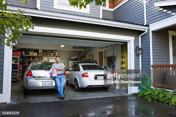 man leaning against washed cars in garage - clean garage stock pictures, royalty-free photos & images