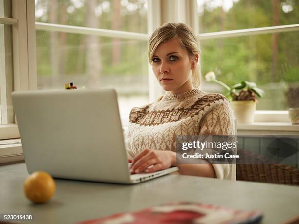 portrait of a woman sitting next to a table using a laptop - corbiscom stock pictures, royalty-free photos & images