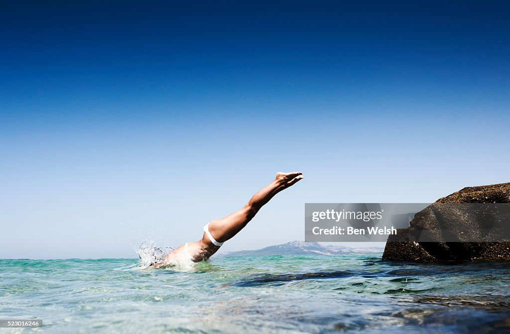 Young woman jumping into sea