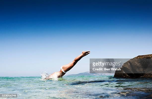 young woman jumping into sea - women in bathing suits stock pictures, royalty-free photos & images
