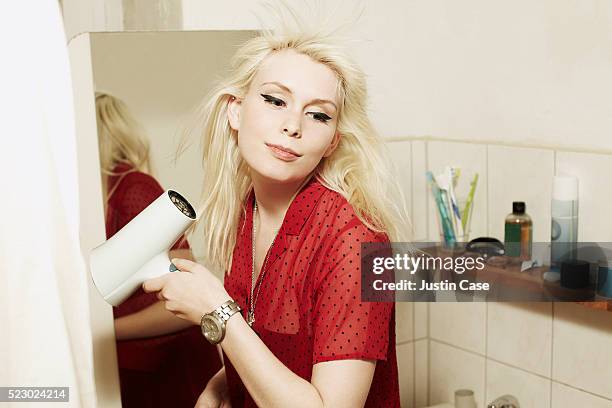 girl drying her hair with a hairdryer in a bathroom - red dress stock-fotos und bilder