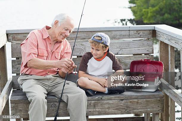 senior man showing grandson how to bait a hook - vintage fishing lure stock pictures, royalty-free photos & images