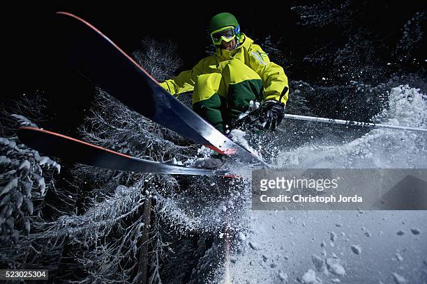young skier jumping of a cliff in a forest at night - night skiing stock pictures, royalty-free photos & images