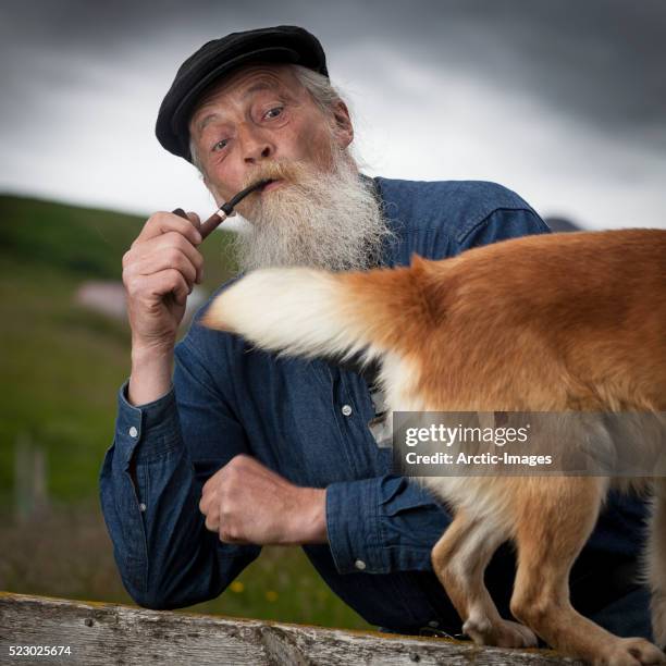 senior man smoking a pipe with dog - bauer pfeife stock-fotos und bilder