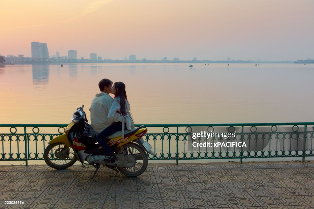 A couple on a motorbike by West Lake during sunset