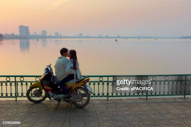 a couple on a motorbike by west lake during sunset - west asia stock-fotos und bilder