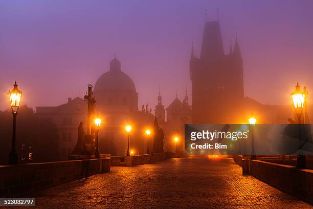 prague, czech republic, charles bridge illuminated in foggy morning - prague stock pictures, royalty-free photos & images