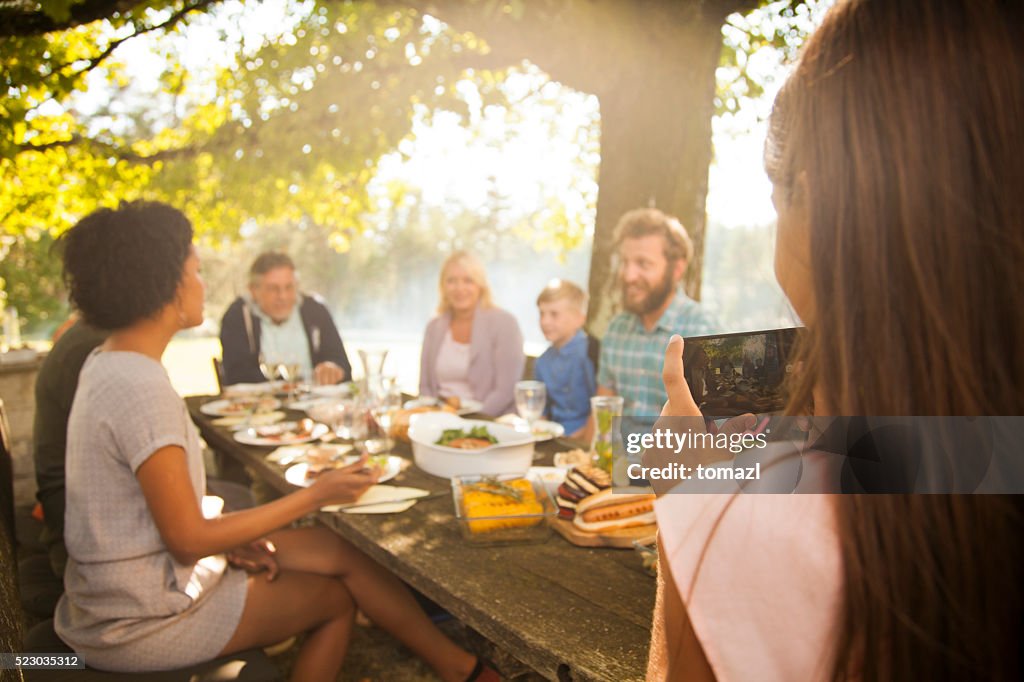 Young girl photographing her family picnic